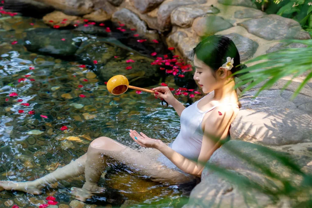 Woman holding a wooden ladle while soaking in a hot spring pool at Riyuegu Hotsprings.