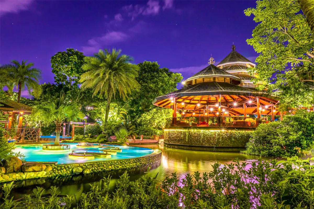 Night view of illuminated pavilion and hot spring pools within the landscaped grounds of Riyuegu Hotsprings.